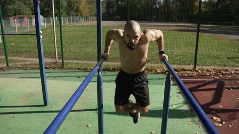 A young handsome man pulls himself up on parallel bars Stock Footage 224860933