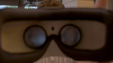 Young handsome man putting virtual reality headgear on the viewer - POV Stock Footage 81844197