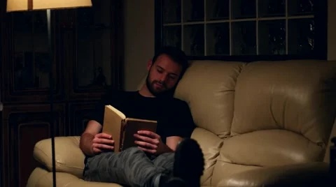 Young handsome man reading book at home Stock Footage 59955717