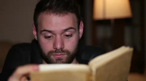 Young handsome man reading book and be surprised at home Stock Footage 59955808