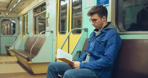 Young handsome man reading a book in the subway car. Portrait view. Stock-Footage 108560072
