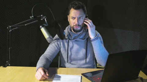Young handsome man reading a note in a recording studio and answering phone Stock Footage 169251795