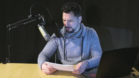 Young handsome man reading text on a sheet of paper in a recording studio. Stock Footage 169251175