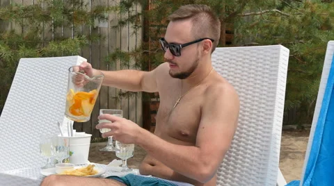 Young handsome man relaxing by the pool, and pet juice from oranges and lemons Stock Footage 53312909