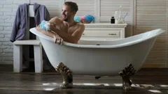 Young handsome man relaxing in the tub. , Stock Video