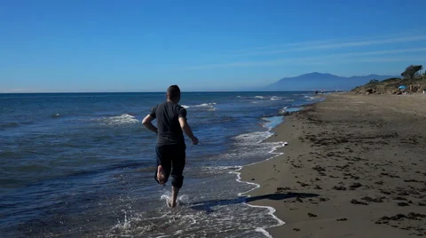 Young, handsome man running on beach, slow motion shot at 240fps Stock Footage 61887695