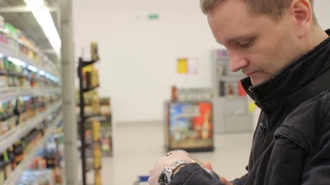 Young handsome man selecting beer can at the supermarket fridge Stock Footage 75524479