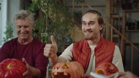 A young handsome man is showing a thumb while making a halloween pumpkin Stock Footage 170270689
