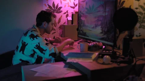 A young handsome man is sitting and eating in front of the computer Stock Footage 128457908