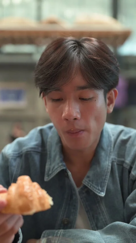 Young handsome man sitting and eating croissant in cafe restaurant Stock Footage 338036028