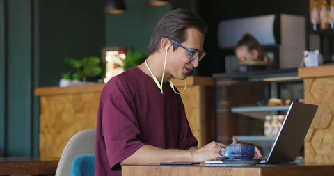 Young handsome man sitting in cafe with laptop making video calling using webcam Stock Footage 164172472
