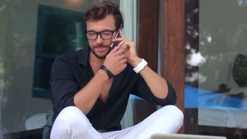 Young handsome man is sitting down on the terrace drinking coffee, talking on Stock-Footage 85525312