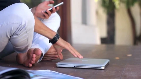 Young handsome man is sitting down on the terrace and using a laptop outside the Stock-Footage 85525391