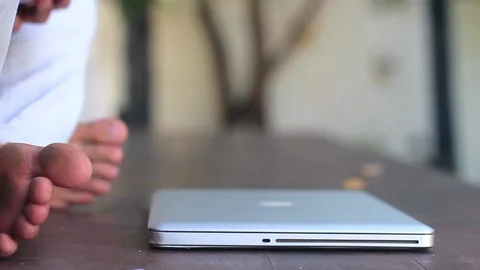 Young handsome man is sitting down on the terrace and using a laptop outside the Video stock 85525473