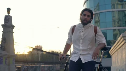 Young handsome man sitting on his bicycle and looking at the camera slow motion Stock Footage 79237637