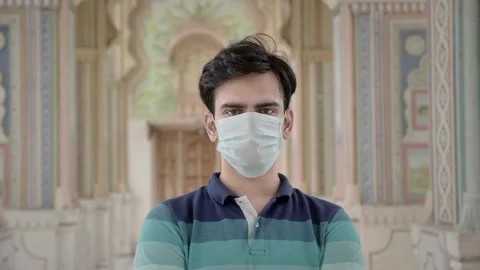 A young handsome man standing in the ancient building wearing face mask Vídeos de archivo 136377399