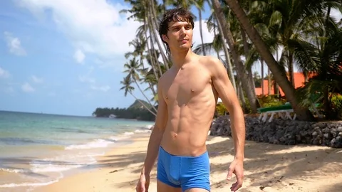 Young handsome man standing sunbathing on the beach, slow motion. 1920x1080 Video stock 88041932