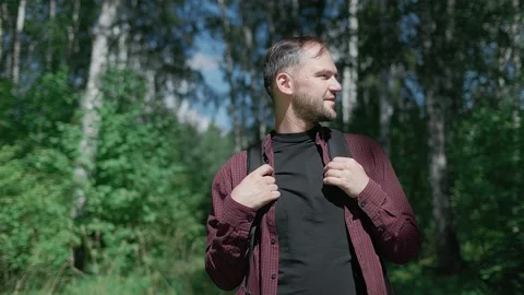 Young handsome man standing in the thicket of the forest looks around and smiles Stock Footage 139208408