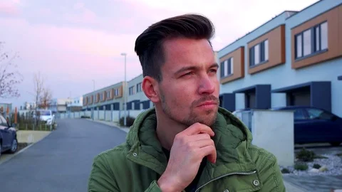 A young, handsome man stands in front of the camera on a road and thinks hard Vidéo 71174727