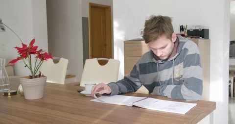 Young handsome man, student studying in his home, checking and reading notes. Stock Footage 124101131