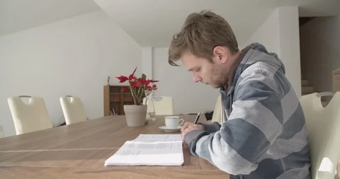 Young handsome man, student studying in his home, checking and reading notes.  Stock Footage 124104767
