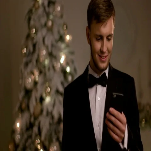 Young handsome man in stylish suit, chatting on mobile phone on New Year day Stock Footage 69493421