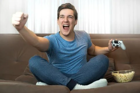 Young handsome man successfully completed mission in video game and looks happy Stock Photos