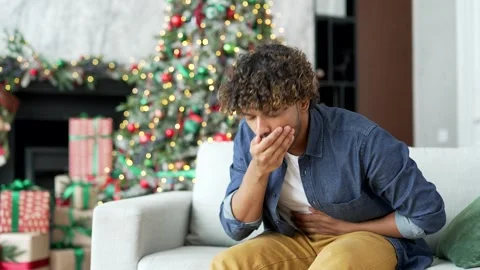 Young handsome man suffering from nausea, wants to vomit sitting on sofa  Stock Footage 253271700