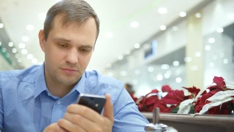 Young handsome man surprised when using a smartphone while sitting in a cafe Video stock 125768977