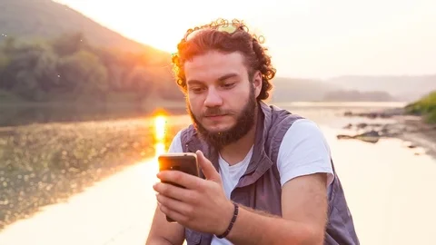 Young handsome man talking on a smartphone in the outdoors. The tourist speaks Stockbeeldmateriaal 81517283