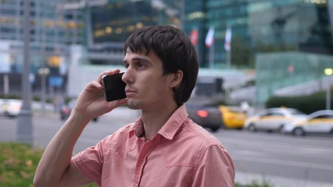 Young handsome Man talking Smartphone stands by the Big Industrial Buildings Stock Footage 124722242