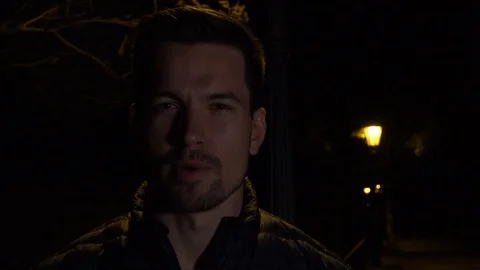 A young handsome man talks to the camera in an urban area at night - closeup - 스톡 동영상 109556439