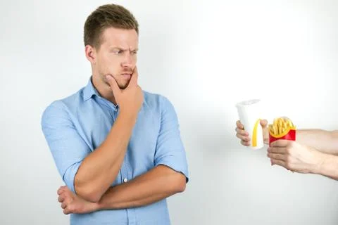 Young handsome man thinks about idea to eat fast food french fries and drink Stock Photos