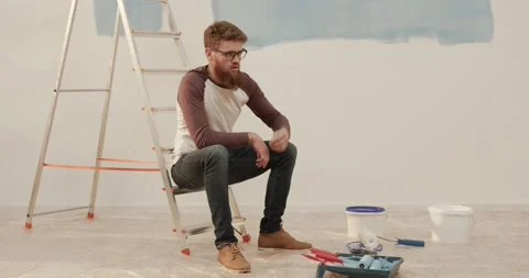 Young handsome man tired of work painting the wall, throws paint roller and Stock Footage 147060006