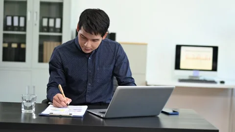 Young handsome man typing on tablet and laptop while sitting at the working.. Video stock 313460772