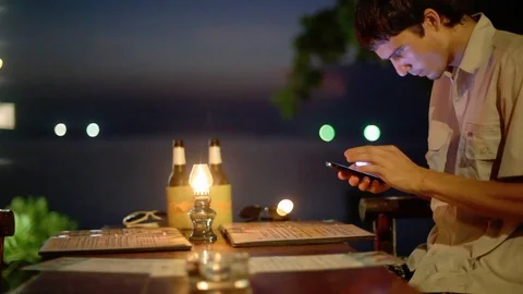 Young handsome man uses smart phone shopping surfing networking and drinks beer Stock Footage 101053418