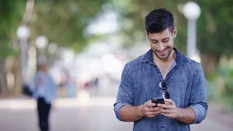 Young handsome man using his phone outdoors, with space for text Video stock 86884115