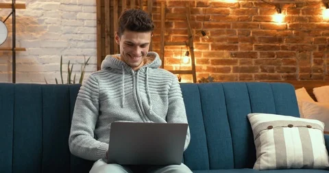 Young Handsome Man using his Laptop at Home, having cute Smile. Man is chatting Stock Footage 126229615
