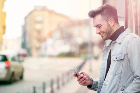 Young handsome man using his cell phone, enjoying a day on the street Stock Photos