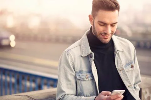 Young handsome man using his cell phone, enjoying a day on the street Stock Photos