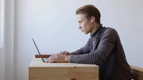 Young handsome man using laptop, scrolling, surfing web, looking at the screen Stock Footage 129007188