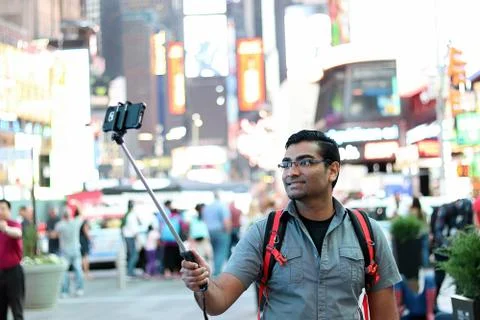 Young handsome man using selfie stick in busy urban city Stock Photos