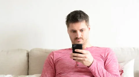 Young handsome man using smart phone in his flat wearing red t-shirt. Stock Footage 53746909