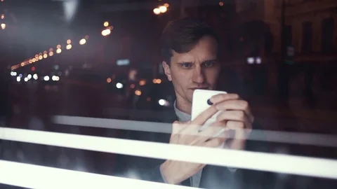 Young handsome man using smart phone on a busy urban street at night Stock Footage 80009158