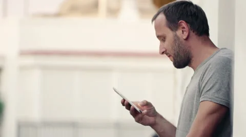 Young handsome man using smartphone while standing on balcony  HD Stock Footage 48648426