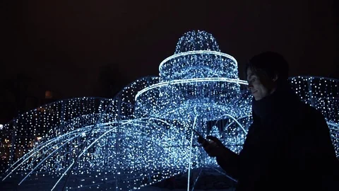 Young handsome man using smartphone standing alone outdoors at night city park Stock Footage 83631202