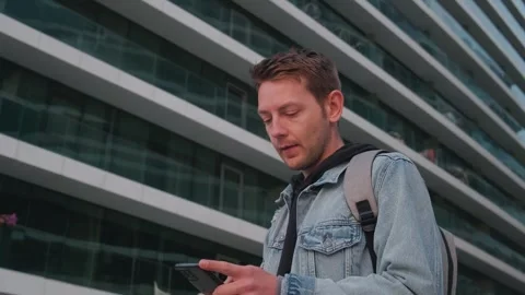 Young handsome man using smartphone outdoor in a city. Caucasian guy texting on Stock Footage 243519556