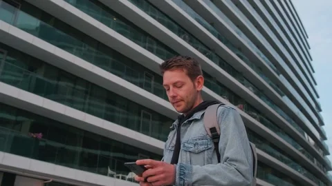 Young handsome man using smartphone outdoor in a city. Caucasian guy texting on Stock Footage 244848634