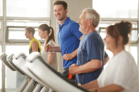 Young handsome man using treadmill in the gym. Stock Photos