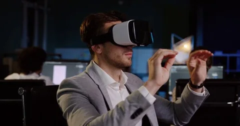 Young handsome man using VR glasses at his workplace late in the evening. VR Stock Footage 82446997